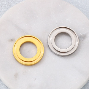 Close-up of gold and silver geometric stainless steel ring charms on marble surface
