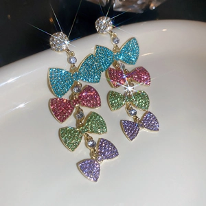 Macro shot of tiered colorful crystal bow earrings with rhinestone tassels and gold finish
