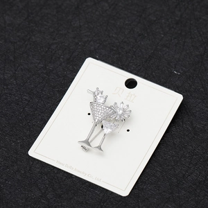 Detailed view of silver cocktail glass brooch with zircon inlay on a display card