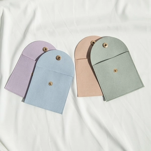 Detail of four colorful microfiber jewelry pouches with snap closures on white fabric