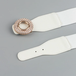Detail of rose gold round buckle with sparkling rhinestones on white elastic belt