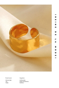 Macro shot of gold-plated irregular textured ring on creamy silk fabric with elegant text