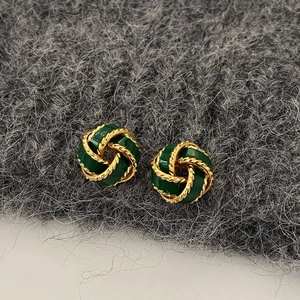 Detailed macro view of vintage gold-plated knot earrings with green enamel inlay