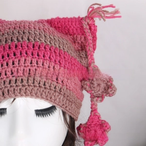 Detail of hand-knitted cat ear hat with pink and brown stripes and star tassels