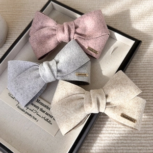 Three velvet bow hair clips in pink, grey and beige with handmade metal labels