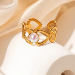 Détail de la bague dorée ajourée de cœurs avec incrustation de nacre ronde