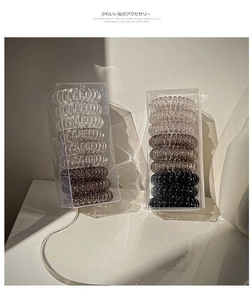 Close-up of grey gradient spiral hair ties set in a transparent minimalist plastic box