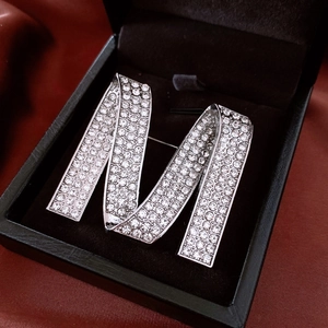 Détail d'une broche lettre M scintillante avec strass dans un coffret cadeau luxueux