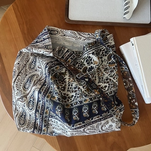 Flat lay of a bohemian paisley tote bag on a wooden table with lifestyle props