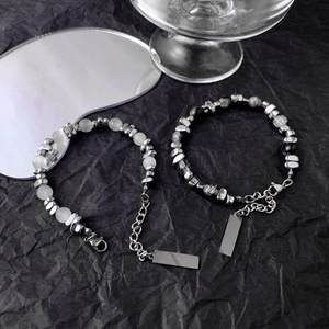 Detail of cat eye and obsidian beads with stainless steel extender and tag on black background