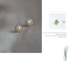 Detail view of pearl stud earrings with diamonds and green clover crystal ball charm