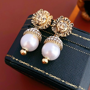 Detailed macro view of golden lion head pearl earrings on a luxury jewelry box