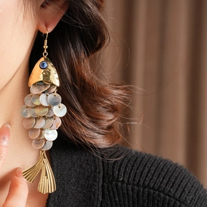 Detailed shot of fish-shaped earrings with gold accents and iridescent shell scales