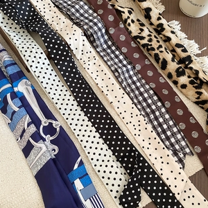 Vista piatta di foulard in seta a quadri e leopardati su un tappetino intrecciato e legno