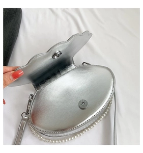 Nahaufnahme der silbernen Muscheltasche mit Magnetverschluss und eleganter Perlenkette