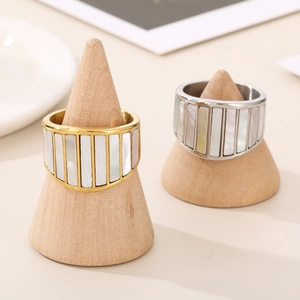 Macro view of wide gold and silver stainless steel rings featuring natural shell inlays