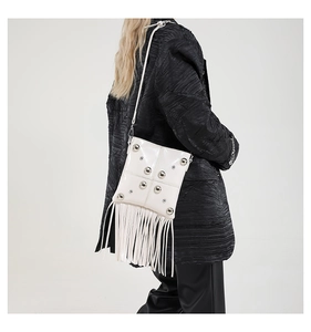 Close-up of a white vintage fringe bag with silver studs and chain strap on a model