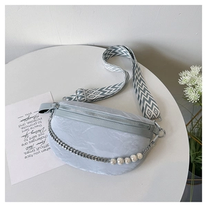 Detail of light blue textured leather crossbody bag with pearl chain and woven strap