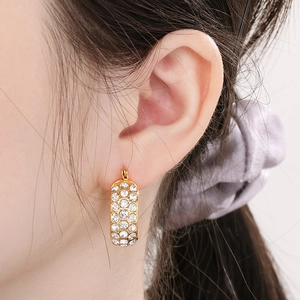 Close-up of elegant gold hoop earrings with sparkling rhinestones on model's ear
