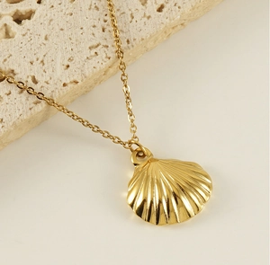 Macro detail of a golden scallop shell pendant on a fine chain over stone backdrop