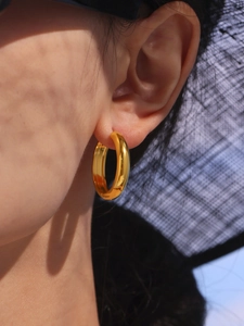 Close-up of polished 18K gold-plated hoop earrings on model with elegant vacation vibe
