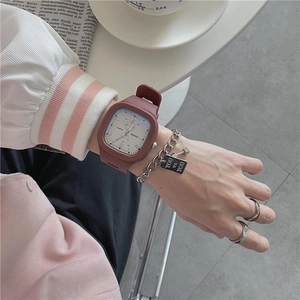 Close-up of a brown square quartz watch with silicone strap and stylish silver jewelry