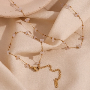 Detail of 18K gold plated chain with pink crystal gravel stones on beige silk cloth