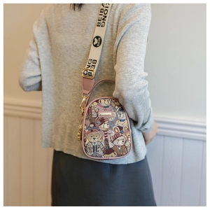 Detailed view of a pink fabric crossbody bag with bear print and wide logo strap
