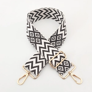 Detail of 5cm wide woven shoulder strap with black white geometric patterns and gold metal clips