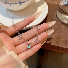 Dettaglio di un bracciale in argento con ciondoli a stella, luna e scettro a cuore