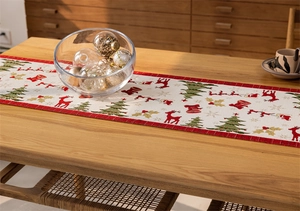 Detail of Christmas table runner featuring reindeer and tree patterns on a wooden table