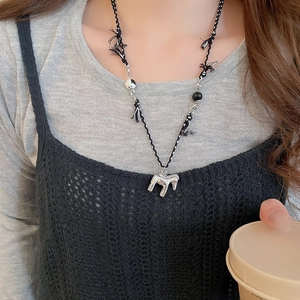 Détail du pendentif cheval plaqué or 18 carats avec pompon noir et cordon tissé