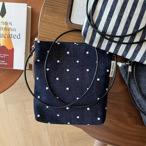 Detail of mini striped and polka dot canvas crossbody bags on a dark wooden surface