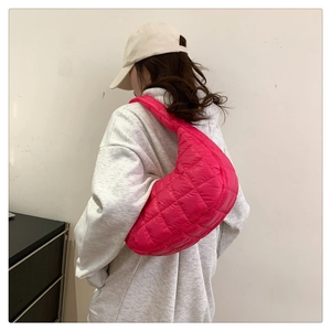 Model wearing a rose red quilted down dumpling bag over a light grey hoodie