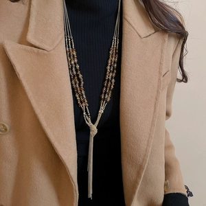 Close-up of ethnic style crystal beaded tassel necklace on a model wearing a winter coat