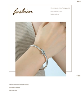 Close-up of a silver-colored knot cuff bracelet in polished titanium steel on wrist