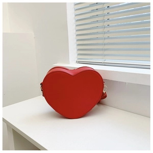 Dettaglio della borsa in pelle rossa a forma di cuore con parti metalliche dorate