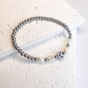 Detail of beaded stainless steel bracelet featuring freshwater pearls and moon charm