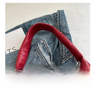 Detail of deep red woven leather handle on a large vintage style shoulder bag
