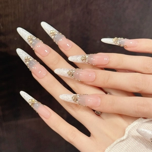 Macro shot of press-on nails featuring golden metal butterflies and sparkling diamonds