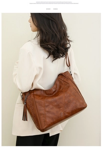 Detail of caramel faux leather bag featuring V-shaped stitching and tassel decorative charm