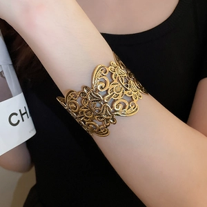Close-up of vintage gold hollow flower cuff bracelet with intricate vine patterns