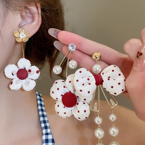 Detail view of handmade fabric bow earrings with red polka dots and white pearls