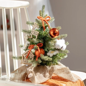 Mini desktop Christmas tree with orange bows and wood ornaments on a white wooden chair
