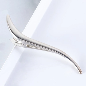 Macro side view of sleek 13.2cm S-shaped silver metal hair clip on white tray