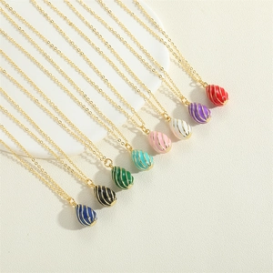 Macro shot of colorful enamel egg pendants with golden spiral patterns on a white tray