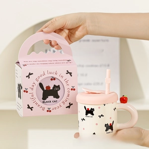 Close-up of cute cat ceramic mug with pink straw and elegant gift box packaging