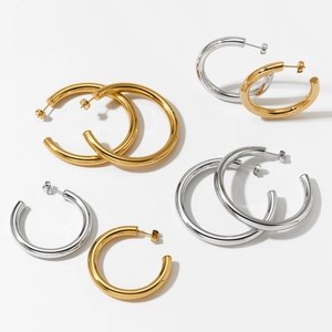 Polished hollow C-shaped hoop earrings in gold and silver plating on a white surface