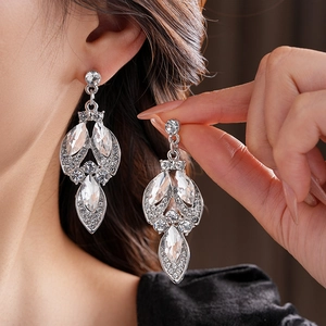 Close-up of silver drop earrings with clear rhinestones worn by a fashion model