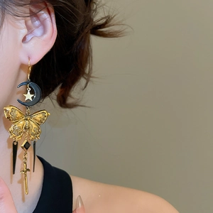 Détail de boucle d'oreille gothique avec papillon, lune et pendentif épée